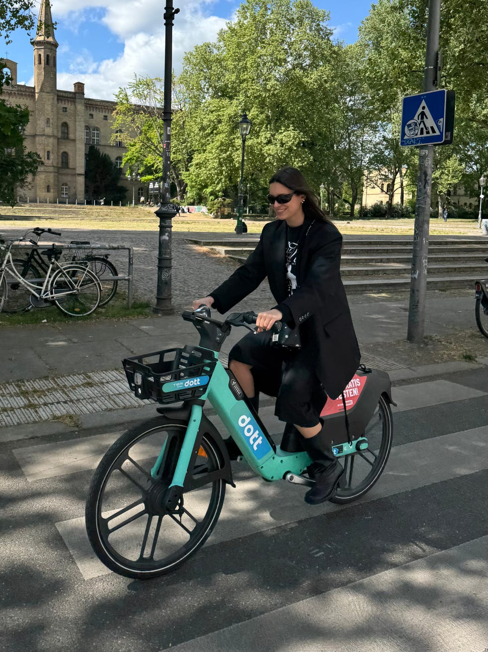 person riding a teal electric bike labeled dott on a city street