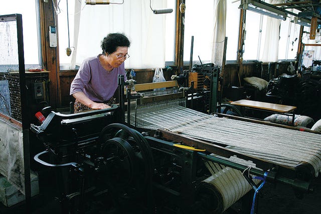 woman operating a weaving machine in a textile workshop