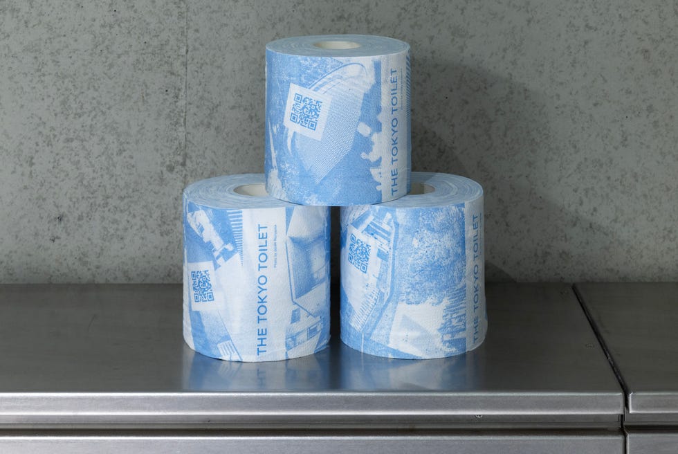 three rolls of toilet paper with blue designs stacked on a silver surface