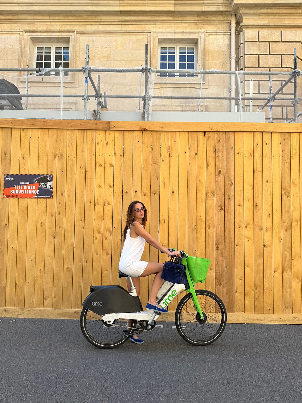 a person riding a lime bike next to a wooden fence