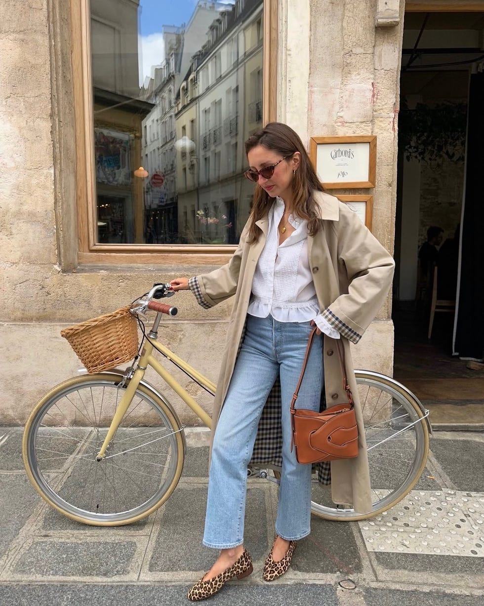 woman standing next to a bicycle on a city street