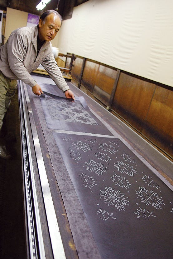 person handling patterned printing plates in a workshop