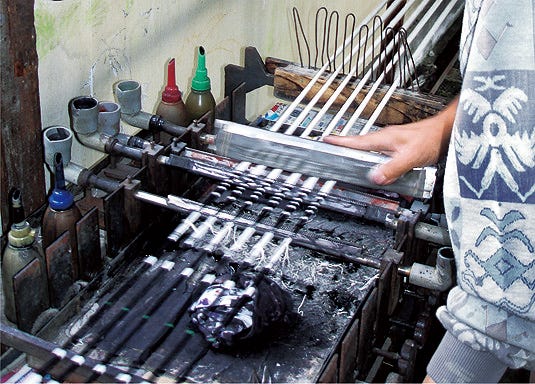 a workspace featuring tools and materials for an artistic process　いしげ結城紬の絣糸作り