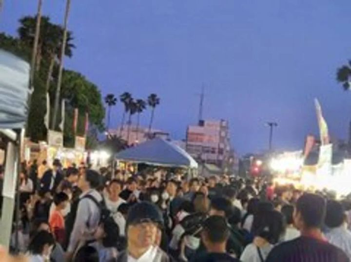 夕暮れ時の全肉祭会場に大勢の来場者が集まり、屋台テントやのぼり旗が並ぶ野外グルメイベントの混雑した通路を写した集客風景