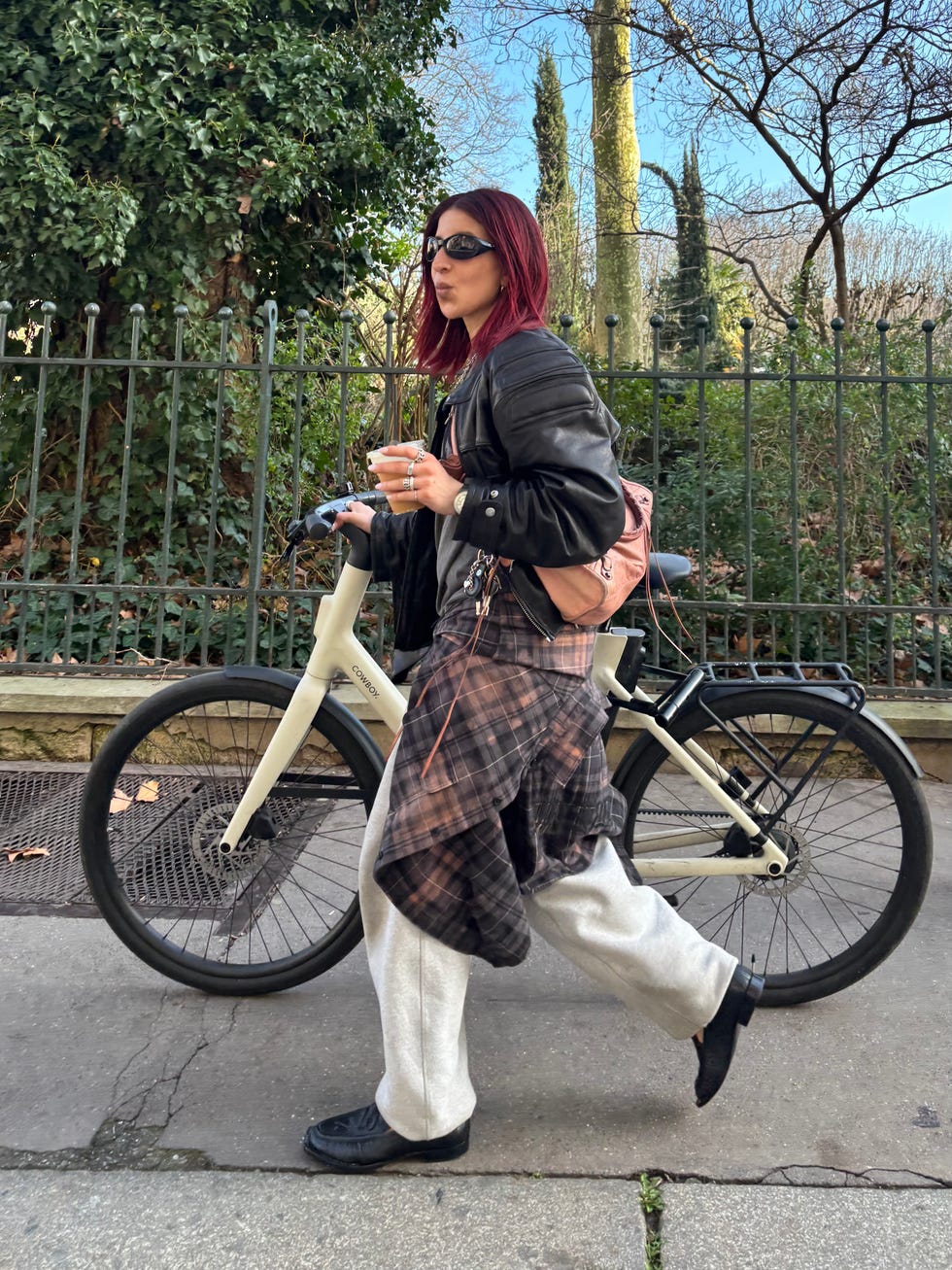 person walking with a bicycle and holding a coffee cup