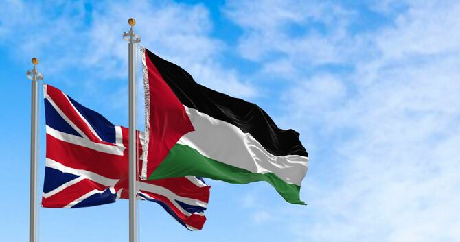 風に揺れるイギリスの国旗とパレスチナの国旗