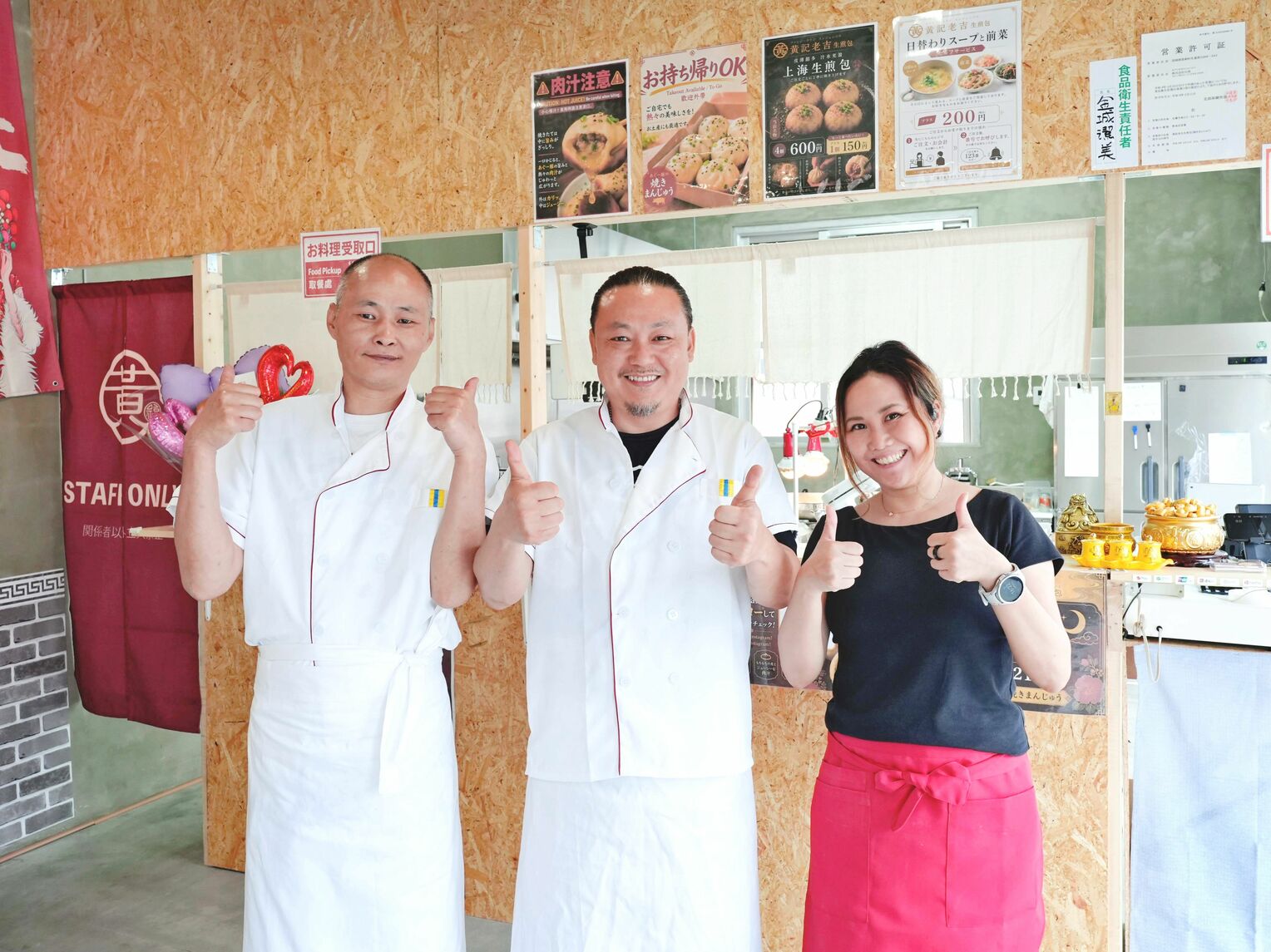 笑顔で店内に立つ(左から)料理人の黄翔さんと、店主の趙晴初さん、金城潔美さん夫妻=22日、名護市東江