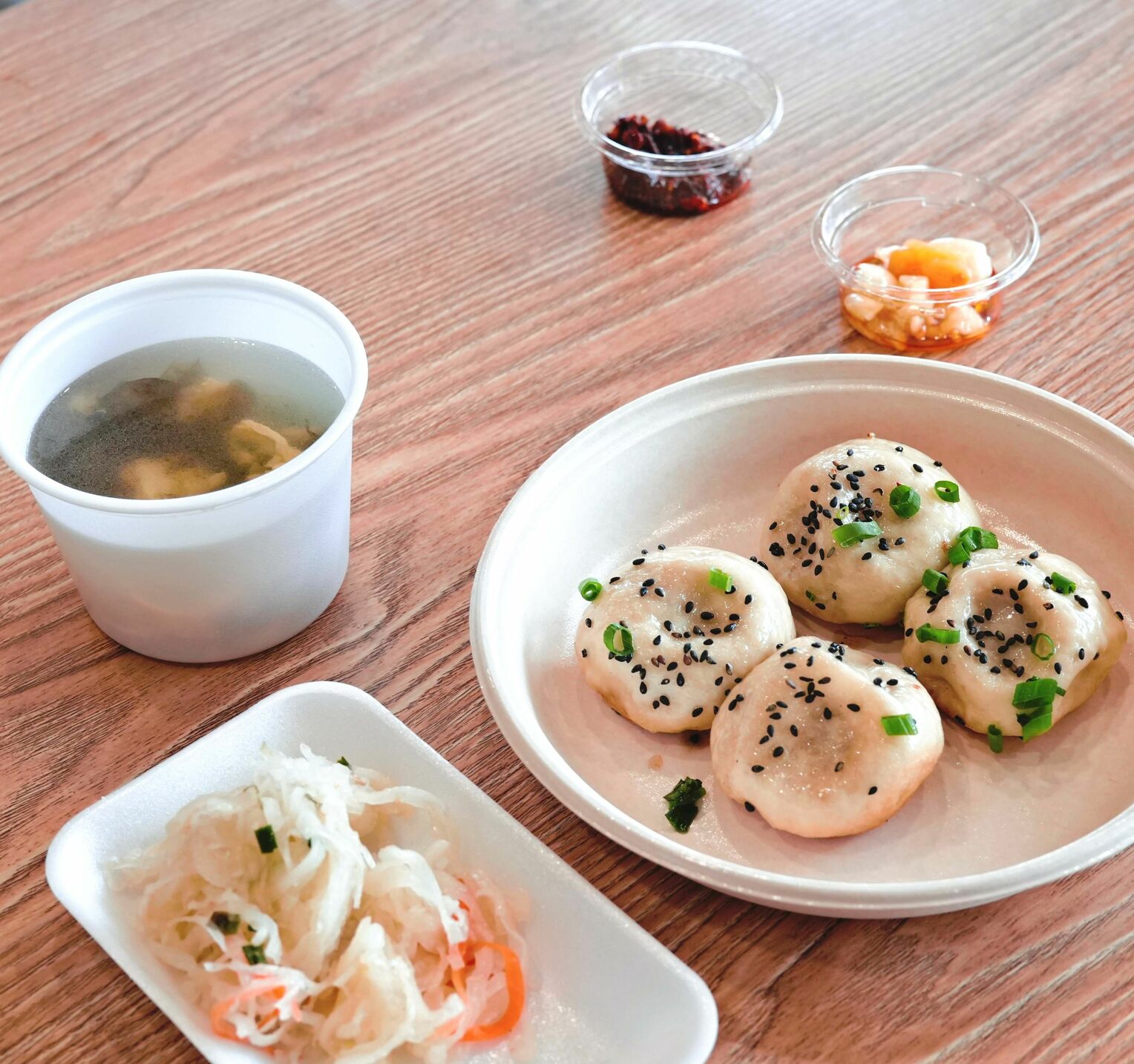 <div class="caption">上海の味「あぐー焼きまんじゅう」は自家製の唐辛子みそとニンニクで味変を楽しめる。手前左は日替わりの小鉢とスープ</div>
