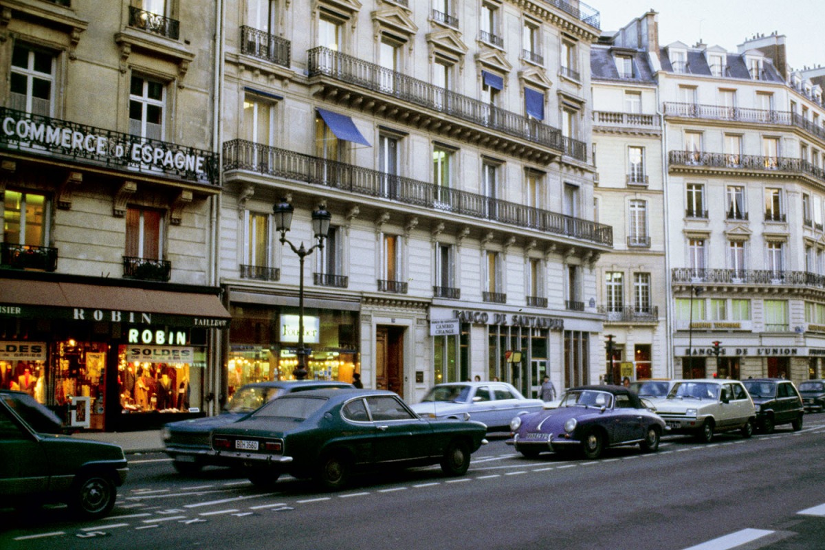 50年前のパリの街角。路上駐車しているポルシェ356やフォード・カプリ、ルノーサンク、メルセデスなどが見える。