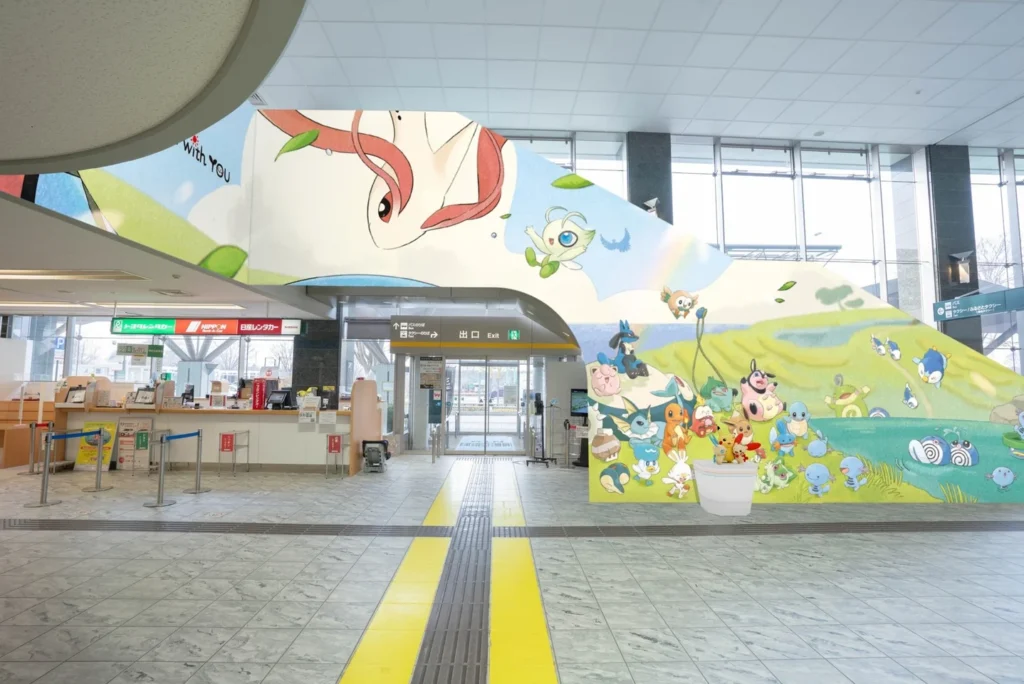 Noto Satoyama Airport terminal decorated with a large Pokémon mural featuring Celebi and dozens of Pokémon on a green hillside