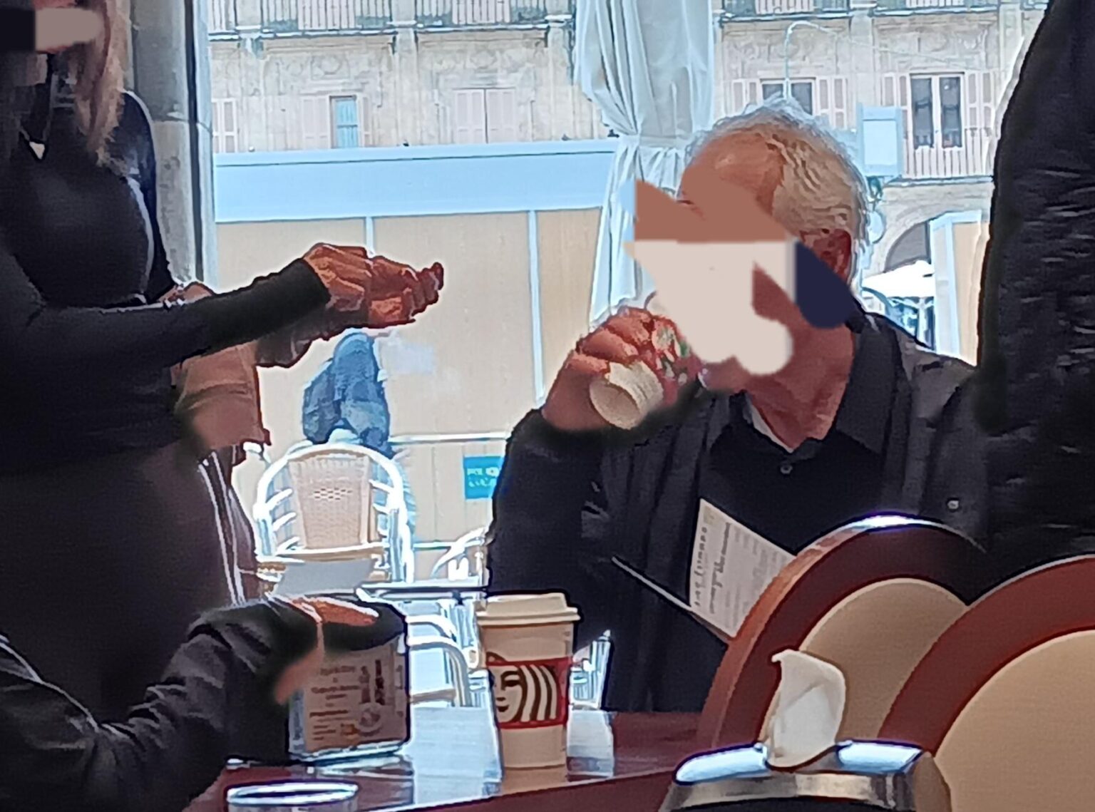 スターバックスのコーヒーを飲みながらサラマンカのマヨール広場にある100周年カフェテリアに入る観光客