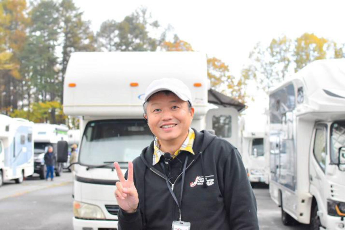 クルマの前でピースサインする男性