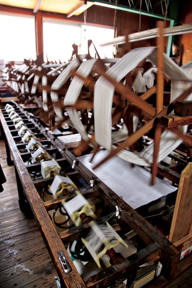 wooden weaving machinery in motion with spools of thread
