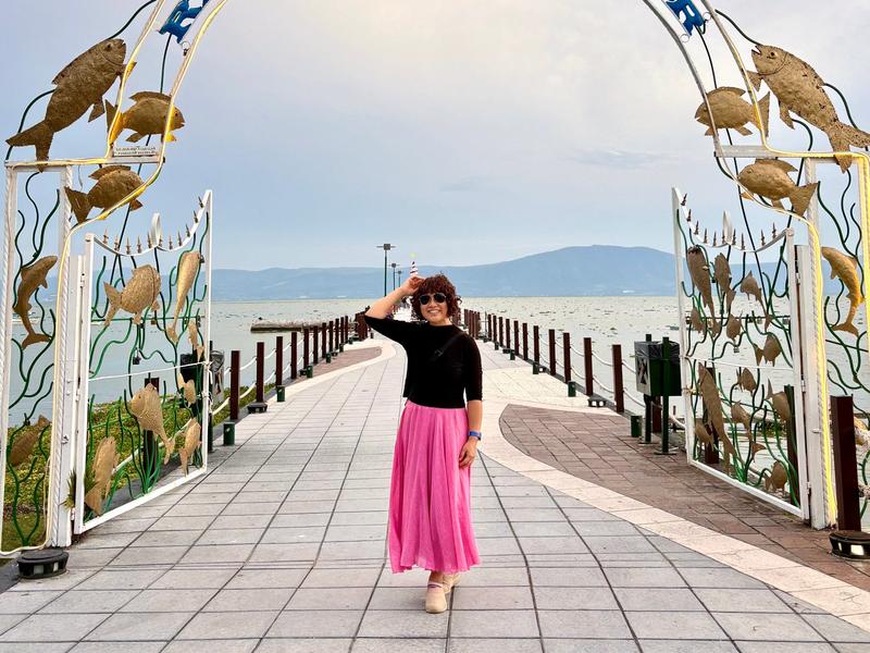 Woman posing below arch on pier