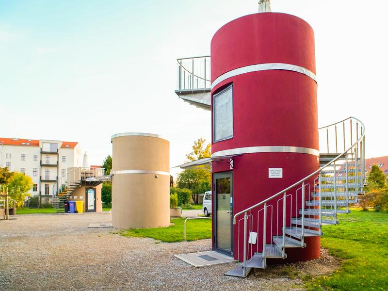Cylindrical homes on a flat property with buildings in the background