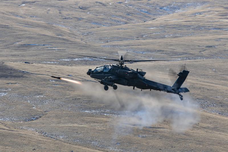 An AH-64E Apache attack helicopter fires a Hellfire missile.