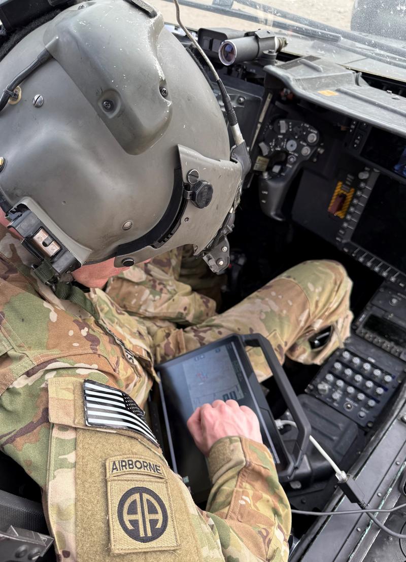A crew member uses an end-user device in an AH-64E Apache.