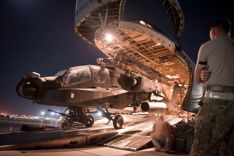 An AH-64 Apache attack helicopter is loaded into a C-5.