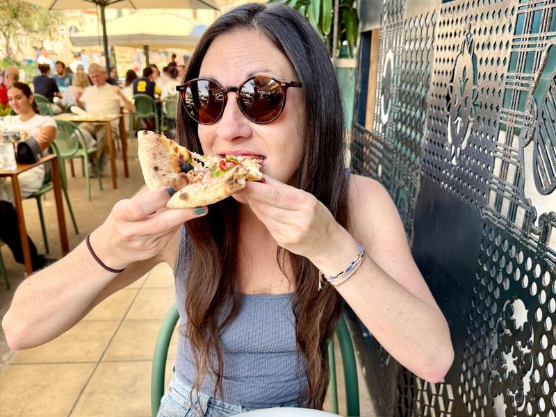 Woman eating slice of pizza in Sicily