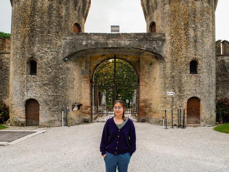 The author stands in front of a castle in Italy on a cloudy day