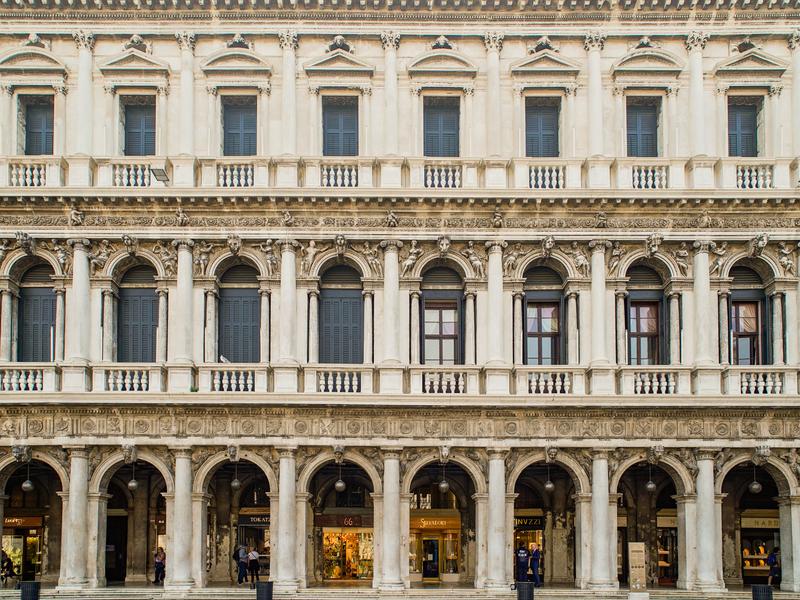 A white, three-story old-world building with pillars in Venice, Italy