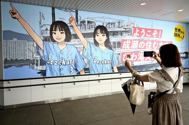 成瀬グッズを持って記念撮影するファンの女性（大津市で）