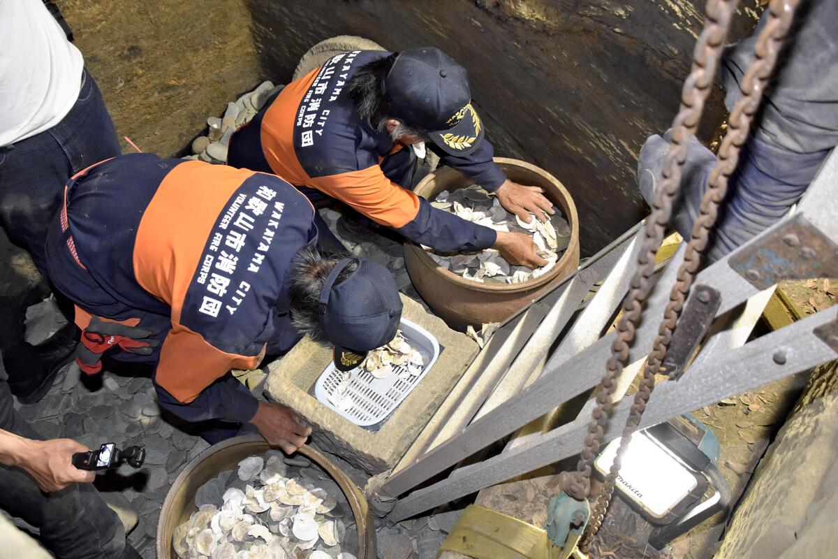 石室で作業する参加者ら。床にはこれまでに納めた経石が敷かれている（和歌山市で）