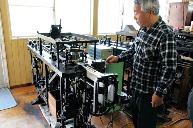a man operating a printing press in a workshop