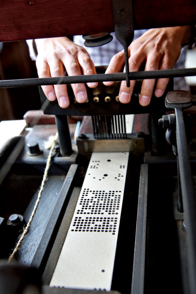 hands operating a mechanical music box or player piano