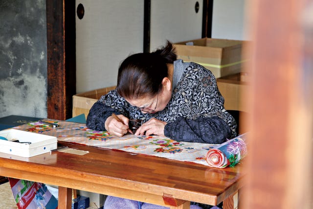 person engaged in intricate crafting work at a table