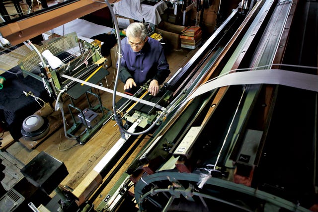 worker operating a weaving machine in a textile workshop