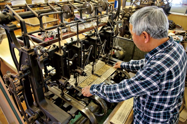 person operating a vintage printing machine