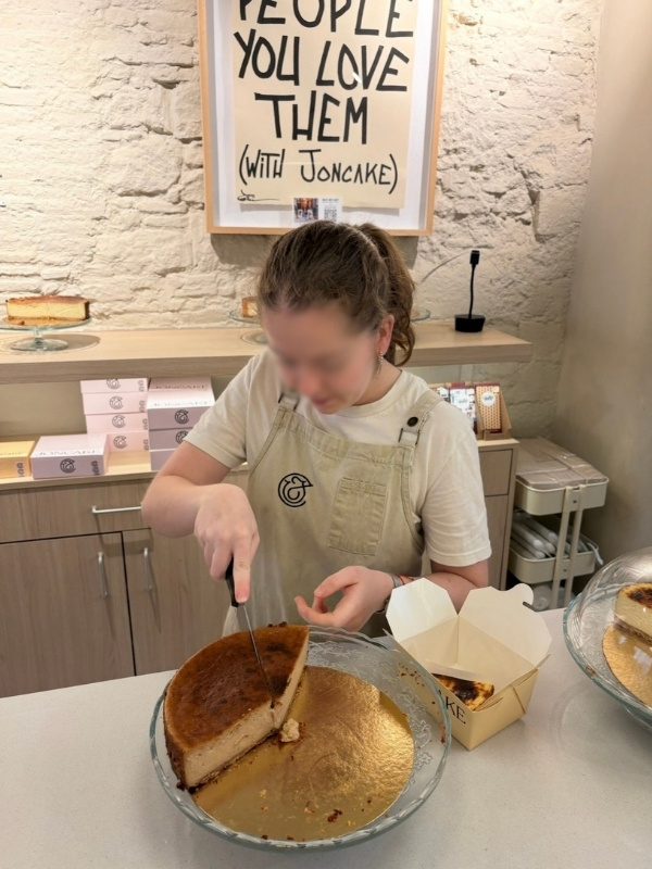 チーズケーキをカットしている店員の写真