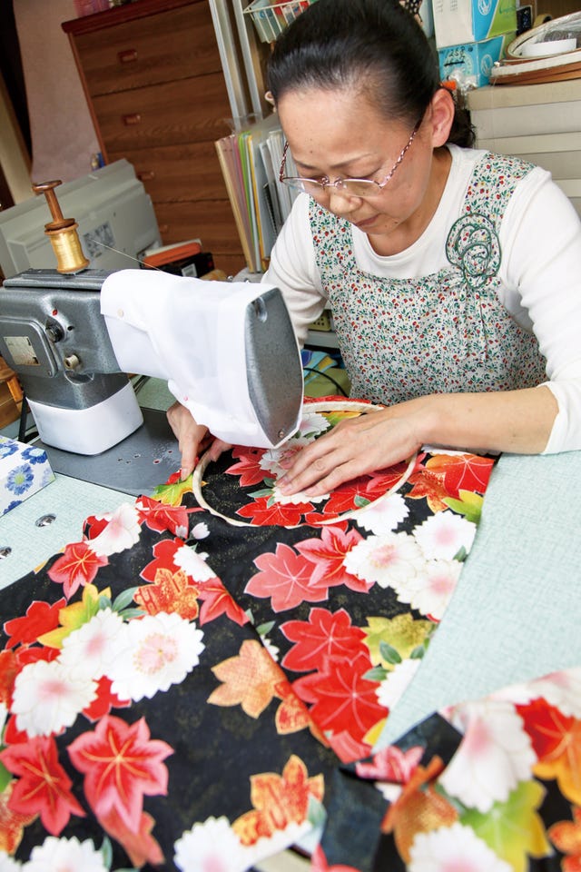 a person sewing intricate fabric patterns using a sewing machine　桐生横振刺繍