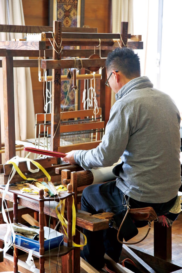 person weaving at a traditional loom