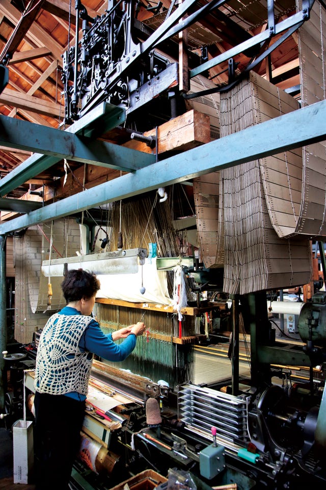a textile worker operating a weaving machine