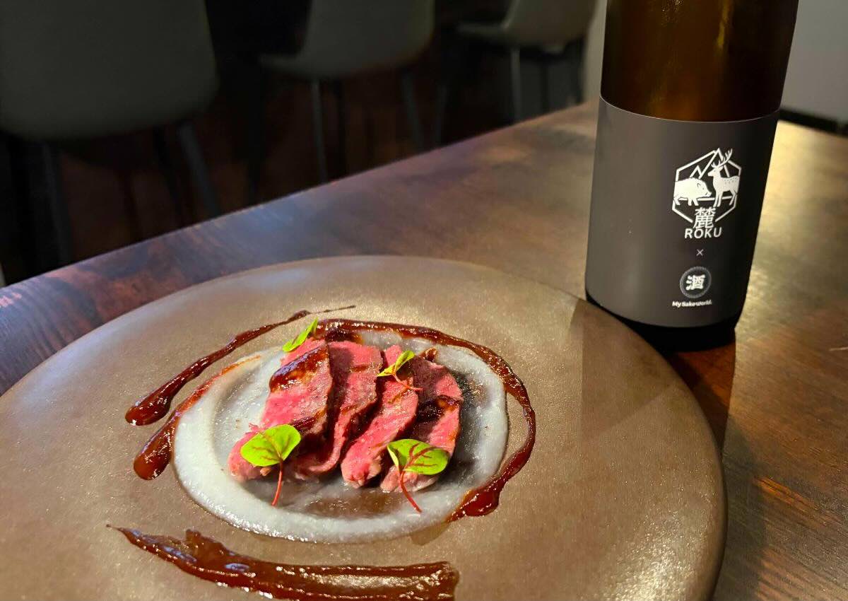 かぶらのソースの上に鹿肉をのせ、アプリコットとポルト酒のソース、さらにマルドンソルトを合わせて食べます。右奥は料理長こだわりのオリジナルブレンド日本酒「ジビエフレンチコース」11,000円　※要予約（その日の食材で料理内容は変わります）