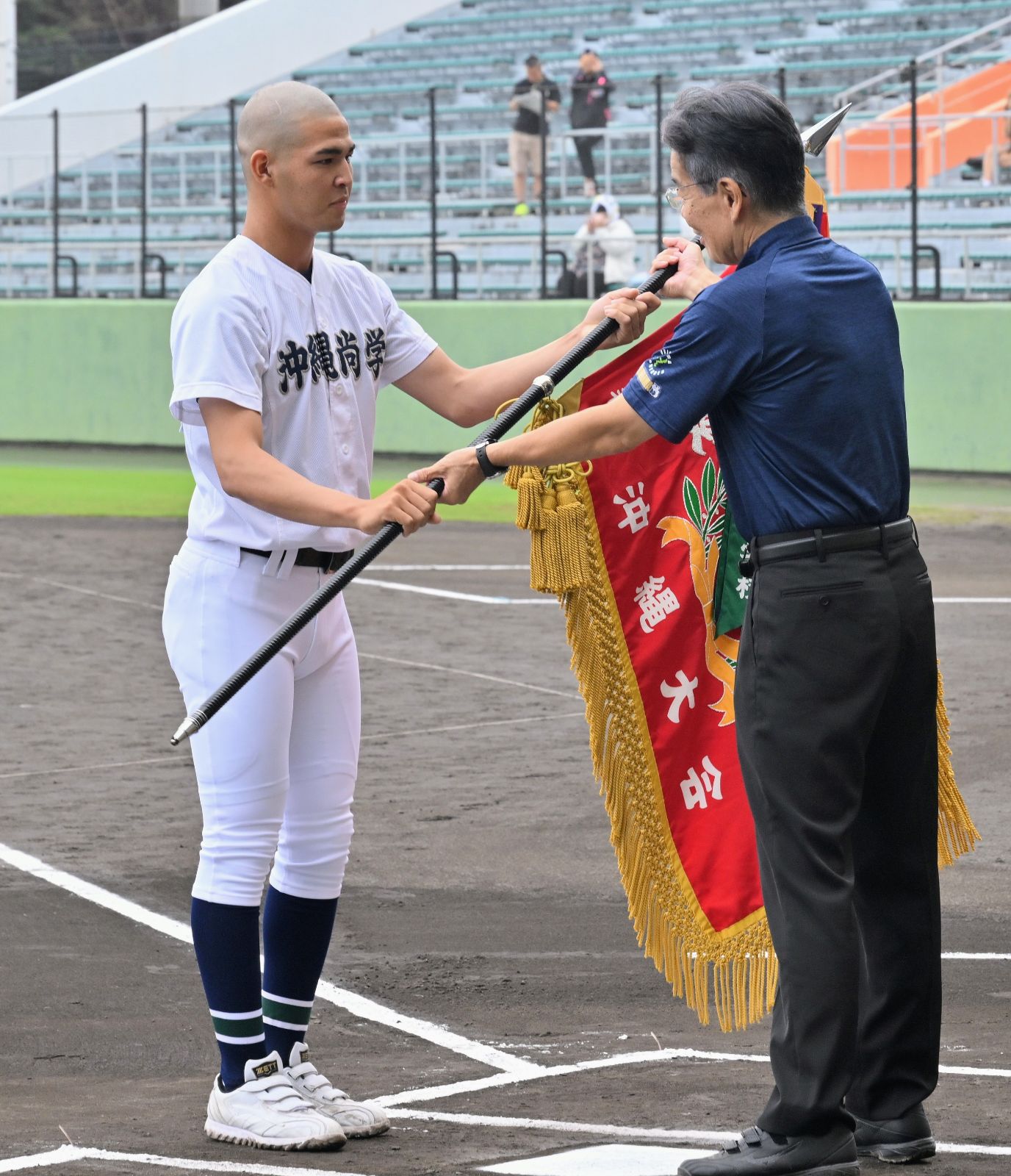前年大会の優勝旗を返還する沖尚の山川大雅主将(左)=13日午前9時22分、沖縄セルラースタジアム那覇(宮城貴浩撮影)