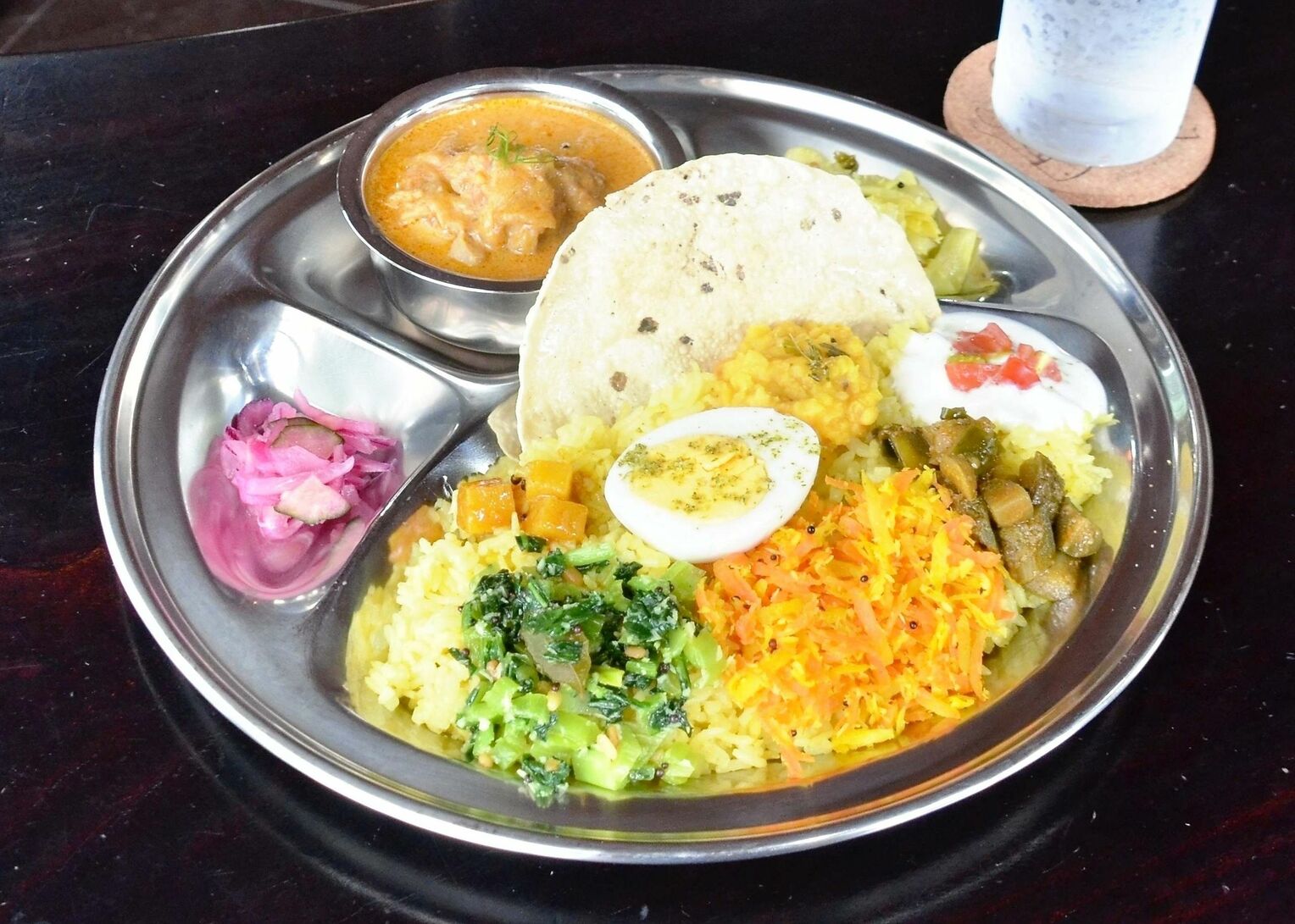10種の「インドおかず」が添えられたココナツチキンカレー。ナスやニンジン、小松菜、キャベツ、大根などおなじみの島野菜が主役
