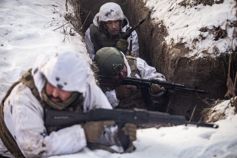 Three Ukrainian soldiers hold rifles while training for trench warfare in Sumy.
