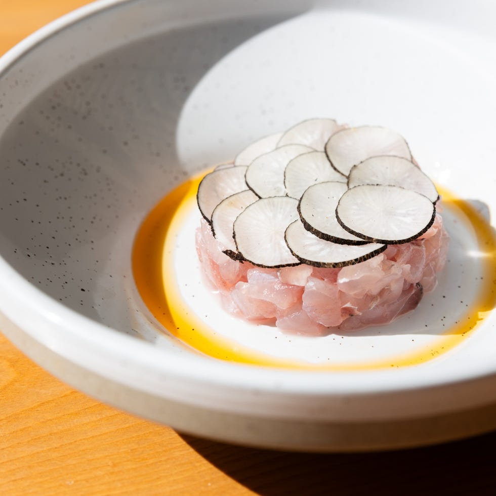 a dish with sliced radishes on top of diced raw fish in a white bowl. a dish with sliced radishes on top of diced raw fish in a white bowl.