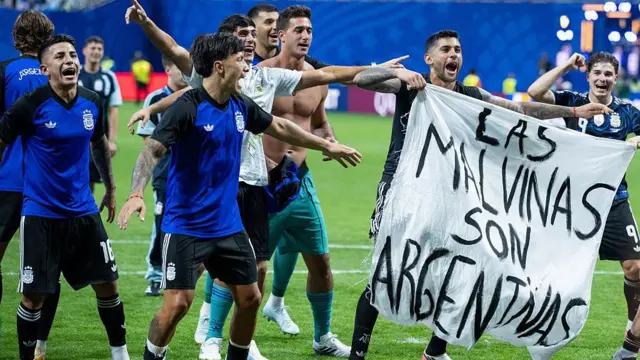 アルゼンチンの選手たちが、白い布に「Las Malvinas son Argentinas」と黒く書かれた幕を手に喜んでいる。青いジャージを着ている選手たちと、脱いでいる選手がいる