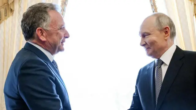ダークスーツ姿のウィトコフ氏とプーチン氏が、笑みを浮かべて向かい合って立っている